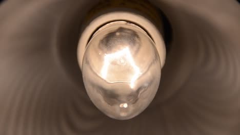 Incandescent-light-bulb-filament-flickering-inside-lamp,-eerie-close-up