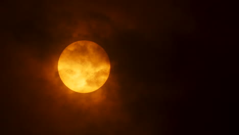 Clouds-pass-over-the-sun-on-a-cloudy-day,-revealing-a-sun-spot