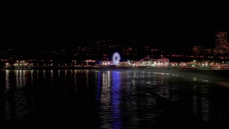 Distant-drone-aerial-shot-at-night-of-the-Santa-Monica-Pier-in-Los-Angeles,-CA