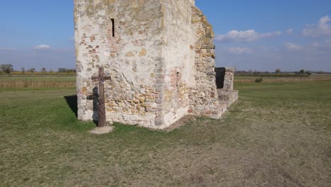 Parallax-around-bottom-half-of-stone-truncated-tower,-cross-in-Soltszentimre,-Hungary