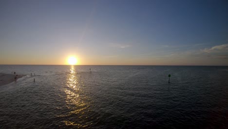 Imágenes-Aéreas-De-Drones-4k-De-La-Puesta-De-Sol-Y-Reflejo-Sobre-El-Mar-En-Una-Playa-Tranquila,-En-Nápoles,-Florida,-EE.UU.