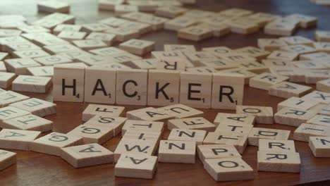 Hand-Legt-Scrabble-Buchstaben-Auf-Die-Kante,-Um-Das-Wort-„Hacker“-Auf-Dem-Tisch-Zu-Bilden