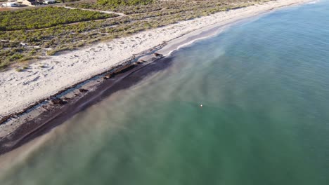 Eine-Drohnenluftaufnahme-Bewegt-Sich-Nach-Unten-Und-Schwenkt-Tiefer-Zu-Einem-Weißen-Sandstrand-In-Australien