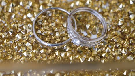 Close-up-of-wedding-rings-on-gold-glitter