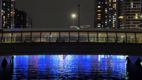 Twilight-cityscape-with-illuminated-buildings-along-the-river,-clear-sky