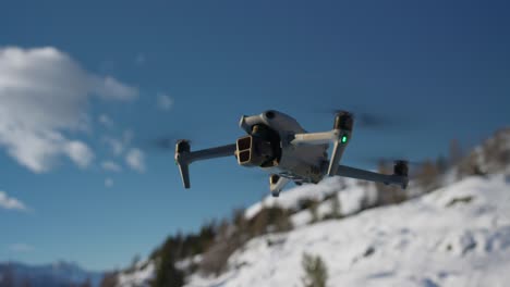 DJI-Mavic-3-Pro-Hovering-In-Mid-Air-With-Snow-Covered-Hillside-In-Background