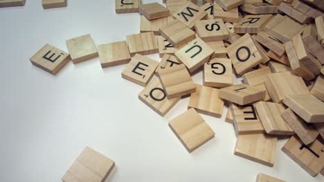 A-pile-of-Scrabble-game-letter-tiles-enter-white-frame-from-right-side