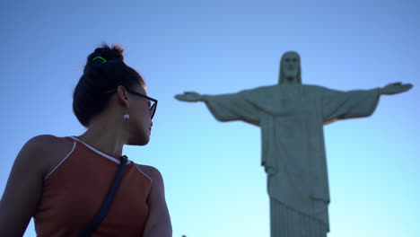 Una-Mujer-Con-Gafas-De-Sol-Posa-Junto-A-Una-Impresionante-Vista-De-Cristo-Redentor-En-Río-De-Janeiro,-Admirando-La-Icónica-Maravilla-Del-Mundo.