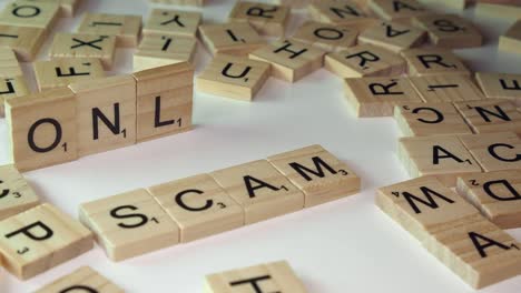 Scrabble-tiles-on-white-table-top-form-words-ONLINE-and-SCAM,-close-up