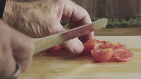 Ältere-Hausfrau-Schneidet-Kirschtomaten-Mit-Scharfem-Messer-Auf-Einem-Küchentisch-Aus-Holz