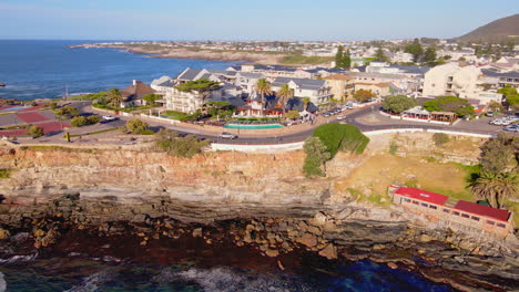 Sea-cliffs-and-iconic-Old-Harbour-of-tourist-destination-Hermanus,-aerial