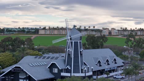 Carlsbad-Windmill-Partial-Circular-Drone-Flight-Directly-In-Front-Moving-Right-To-Left-With-Parallax-Effect-Green-Flower-Fields-In-The-Background