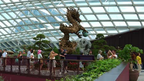 Panning-view-capturing-the-interior-of-Flower-Dome-glass-greenhouse-conservatory,-featuring-a-wooden-dragon-sculpture-during-festive-season,-to-celebrate-Lunar-new-year-at-Gardens-by-the-bay