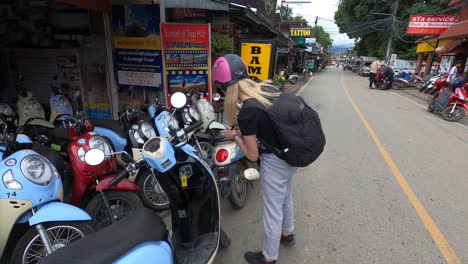 Young-blonde-woman-with-helmet-photographing-a-scooter-at-rental-shop