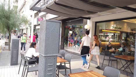 Local-people-walk-at-urban-coffee-in-buenos-aires-city-streets-avenue-in-autumn,-bar-tables,-chatting-and-having-coffee