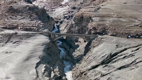 Toma-Panorámica-Aérea-Puente-Sumergido-Lago-Chevril-Tignes-Saboya-Francia-Durante-El-Drenaje-Del-Río-De-Invierno