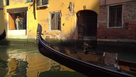 Gondola-with-venetian-oarsmen-gondolier-and-tourists-sails-through-water-canal-in-Venice