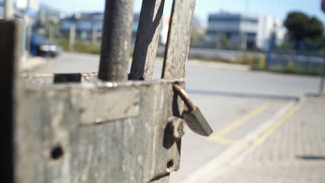 Close-up-shot-on-old-rusty-padlock,-high-car-traffic-in-the-blurry-background-4K