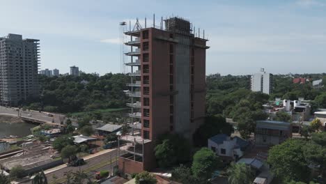 Dynamic-drone-footage-sweeps-around-a-construction-site,-revealing-the-bustling-cityscape,-lush-trees,-and-winding-roads-in-stunning-detail