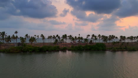 Atardecer-Nublado-En-La-Playa,-Vista-Del-Atardecer-Junto-A-La-Playa-Desde-El-Lado-Del-Lago-Con-Palmeras