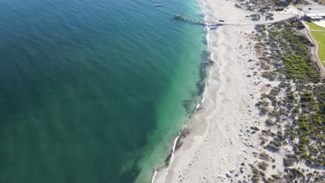 Drone-aerial-panning-up-over-pristine-blue-water-and-a-white-sand-beach-in-Australia