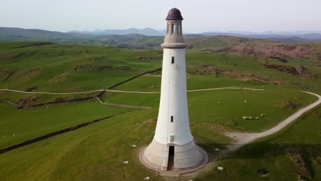 Aerial-tilt-up-shot-revealing-the-Sir-John-Barrow-Monument-on-a-sunny-day,-showcasing-its-stature-and-the-surrounding-landscape