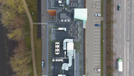 Drone-shot-of-office-building-roof-with-solar-panels,-heating,-ventilation-and-air-conditioning-equipment