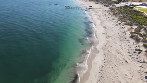 Drohnenluftaufnahme,-Die-Sich-An-Einem-Sonnigen-Tag-Vom-Jurien-Bay-Town-Pier-Mit-Blauem-Wasser-Rückwärts-Bewegt