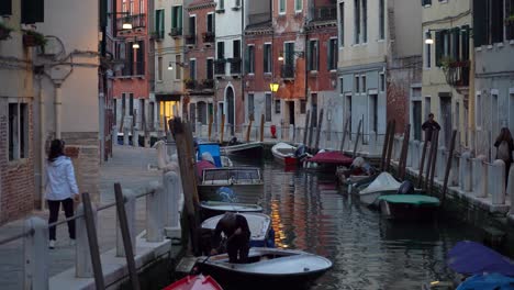 Old-Italian-Cleans-his-Boat-that-is-Parked-in-Water-Canal-in-Venice