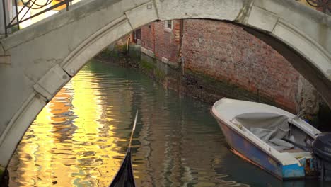 Gondolier-with-gondola-sails-a-couple-of-tourists-in-one-of-many-water-canals-in-Venice