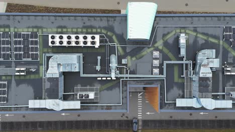 Drone-shot-of-office-building-roof-with-solar-panels,-heating,-ventilation-and-air-conditioning-equipment