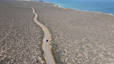 Drohnenaufnahme-Eines-Wohnmobils,-Das-Auf-Einer-Landstraße-An-Einem-Wunderschönen-Meer-Entlang-Fährt