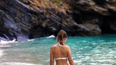 Woman-in-bikini-walks-along-the-beach.-Slowmotion
