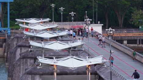 Healthy-lifestyle,-people-riding-bike,-jogging,-strolling-across-the-reservoir-at-Marina-Barrage,-serves-as-a-water-management-facility-for-irrigation,-flood-control,-and-water-supply-in-Singapore