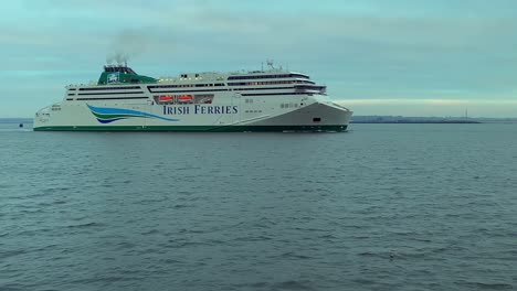 Speed-ramped-Irish-ferry-exits-Dublin-Harbor,-red-lighthouse-in-view