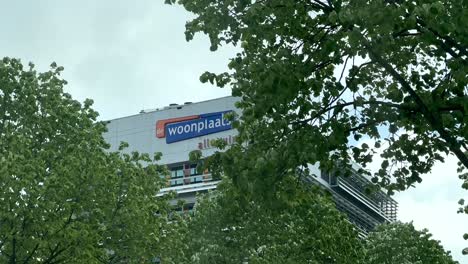 De-Woonplaats-Company-Building-in-Dutch-Town-behind-green-trees-at-cloudy-day