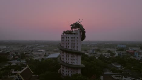 Luftaufnahme-Des-Faszinierenden-„Drachentempels“-Wat-Sam-Phran,-Einem-Bemerkenswerten-17-stöckigen-Zylindrischen-Rosa-Tempel,-Der-Mit-Einem-Kolossalen-Grünen-Drachen-Geschmückt-Ist,-Der-Das-Bauwerk-Umgibt