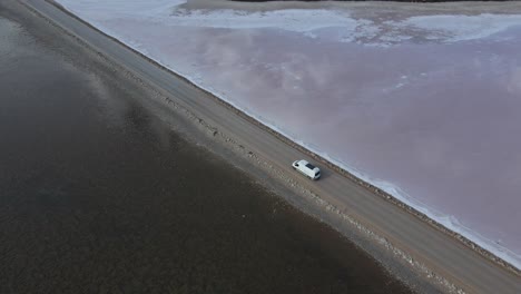 Drone-aerial-over-campervan-on-road-over-pink-lake-MacDonnell-in-South-Australia