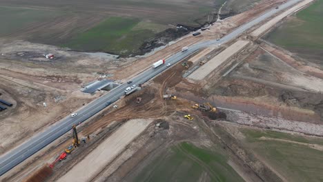 Drone-shot-of-the-road-under-construction-for-the-expansion-project,-there-is-a-huge-construction-site-with-the-equipment-for-work