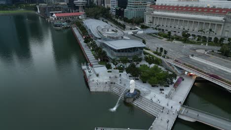 Gente-Corriendo-Y-Relajándose-En-El-Paseo-Marítimo-Del-Parque-Merlion-Con-Vistas-Modernas-A-La-Ciudad-En-El-Fondo,-Disparo-De-Arco-De-Drones