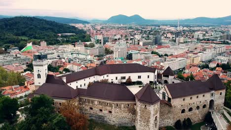 Toma-Panorámica-Aérea-Del-Castillo-De-Liubliana-En-Eslovenia,-Que-Muestra-El-Contraste-Del-Casco-Antiguo-Con-El-Horizonte-Moderno-De-La-Capital.