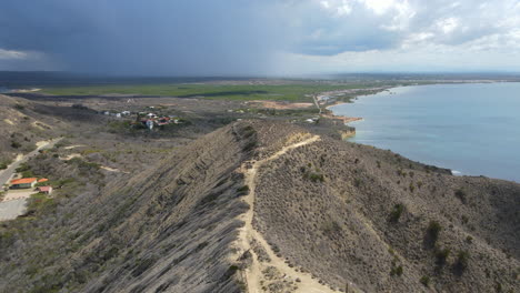 Aerial-rising-wide-shot-of-path-on-mountain-hills-in-Monte-Cristi-during-cloudy-day