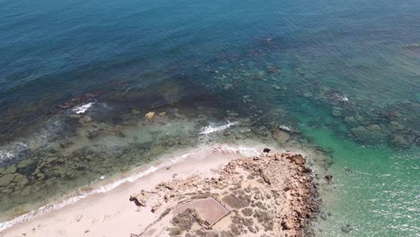 Drone-aerial-with-a-slow-pan-of-the-ocean-with-multiple-blue-colours-on-a-sunny-day