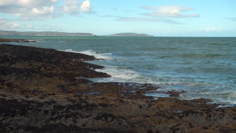 Wide-shot-of-waves-was-they-violently-crash-on-rocks-on-the-Irish-coastline