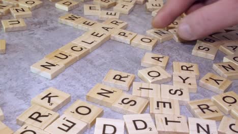 NUCLEAR-and-WEAPONS-form-crossword-from-Scrabble-letter-tiles-on-table