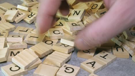 Männliche-Rechte-Hand-Wählt-Unter-Verschiedenen-Scrabble-Spielsteinbuchstaben