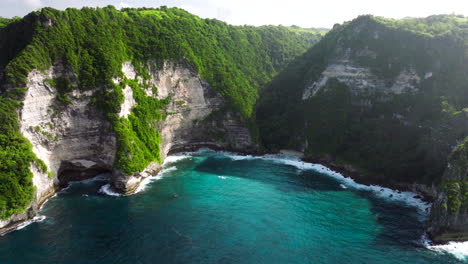 Cliffs-of-vegetation-and-limestone,-turquoise-ocean-water,-bay-location