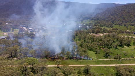 Backward-aerial-shot-of-fire-caught-in-Crackenback-leading-to-smoke-in-NSW,-Australia