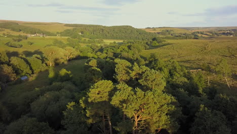 Drone-flies-over-farmland-campsite-in-Northumberland,-England-at-sunset