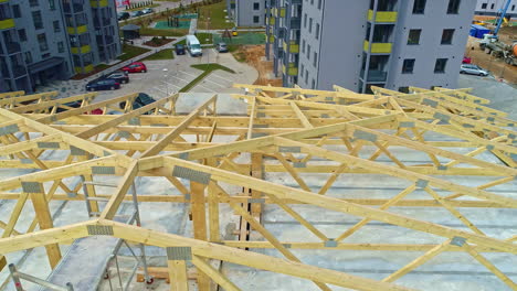 Closeup-shot,-wooden-house-architecture-being-built,-structure-aerial-city-shot-near-to-car-parking-and-highway-background